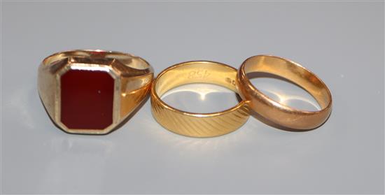 A 22ct yellow gold engraved wedding band, a similar plain band and a 9ct yellow gold signet ring with carnelian matrix.